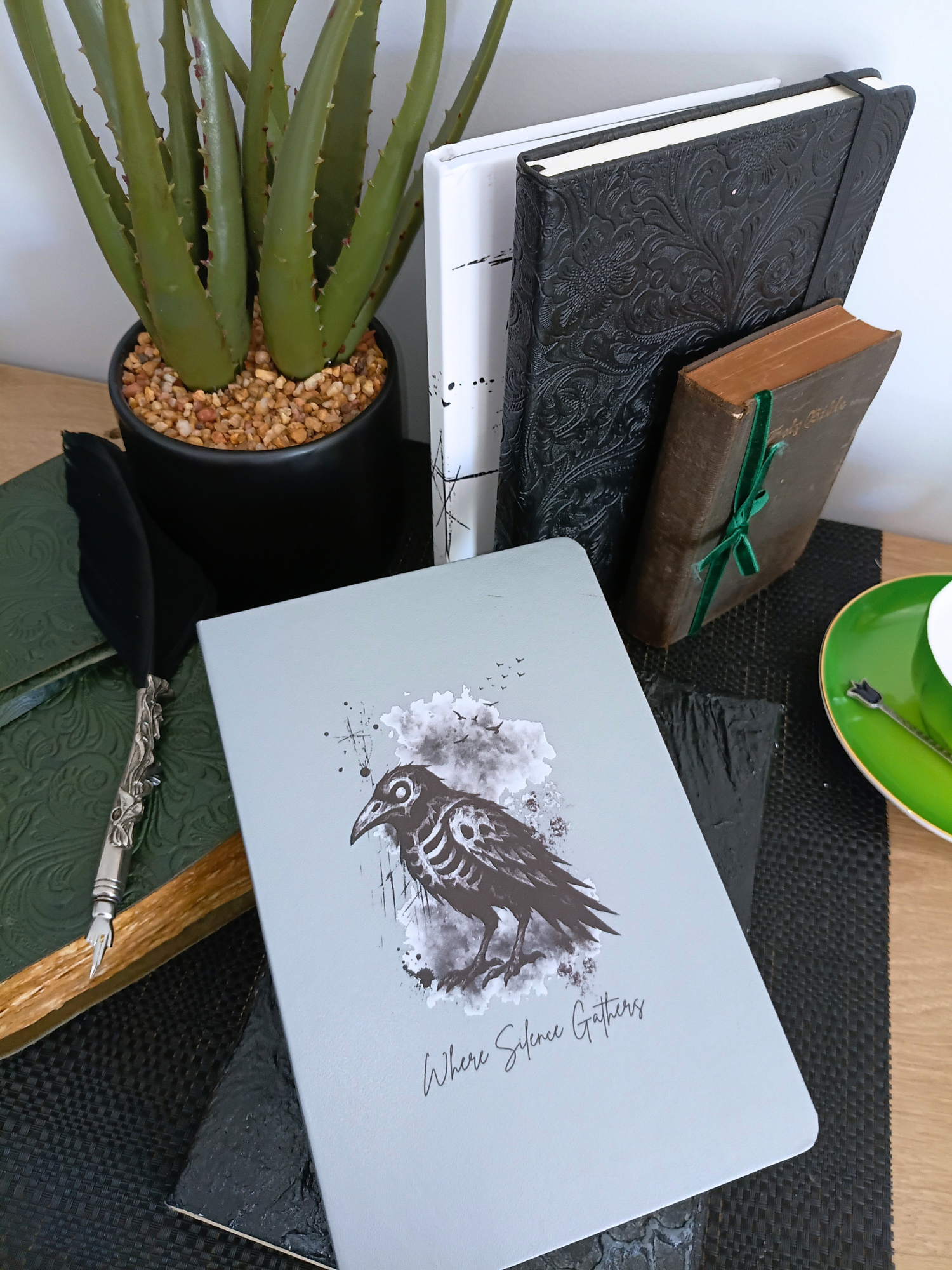 Notebook with a bird illustration on a desk with a plant and books in the background