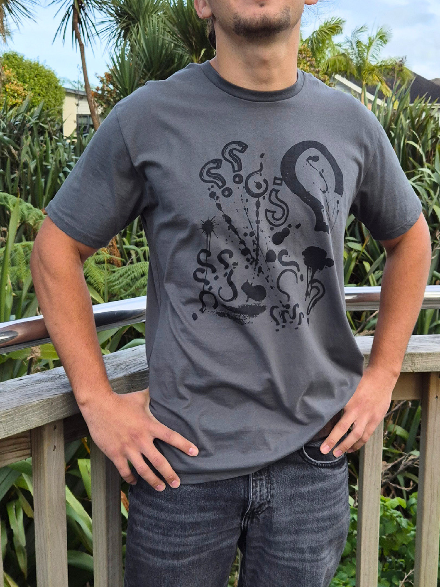 Person wearing a gray t-shirt with a black graphic design outdoors.