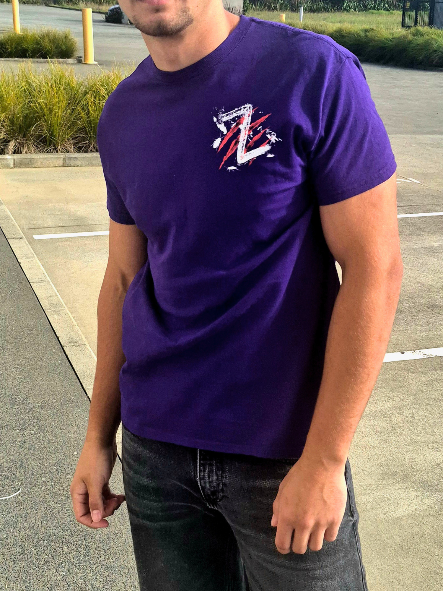 Person wearing a purple t-shirt with a logo in an outdoor setting